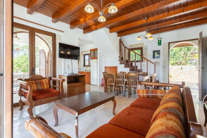 Open-plan living room with sofa, dining area, kitchen, ornamental fireplace, WiFi internet, satellite TV, DVD player, and pool terrace access . - Kefalas Villas Collection . (Fotogalerie) }}