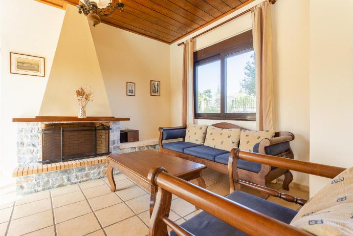 Open-plan living room with sofa, dining area, kitchen, ornamental fireplace, WiFi internet, satellite TV, DVD player, and pool terrace access . - Kefalas Villas Collection . (Galleria fotografica) }}