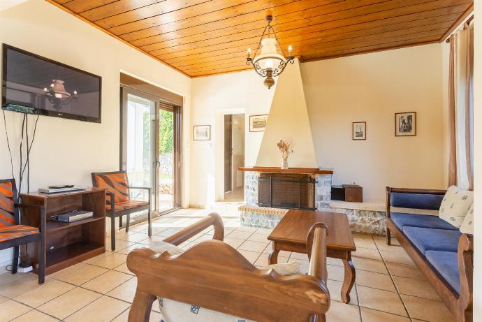 Open-plan living room with sofa, dining area, kitchen, ornamental fireplace, WiFi internet, satellite TV, DVD player, and pool terrace access . - Kefalas Villas Collection . (Galerie de photos) }}