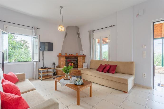 Open-plan living room with sofas, dining area, kitchen, ornamental fireplace, A/C, WiFi internet, TV, DVD player, and terrace access . - Kalyves Villas Collection . (Galerie de photos) }}