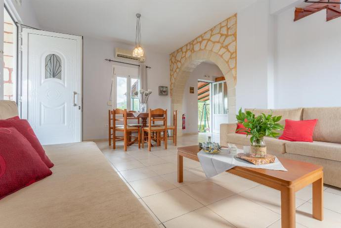 Open-plan living room with sofas, dining area, kitchen, ornamental fireplace, A/C, WiFi internet, TV, DVD player, and terrace access . - Kalyves Villas Collection . (Galleria fotografica) }}