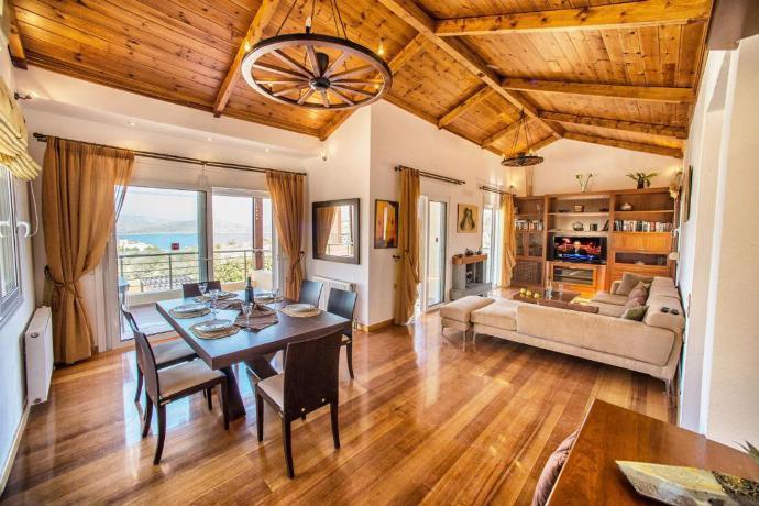 Open-plan living room with sofa, dining area, kitchen, ornamental fireplace, A/C, WiFi internet, satellite TV, and terrace access with sea views . - Villa Glan Y Mor . (Photo Gallery) }}