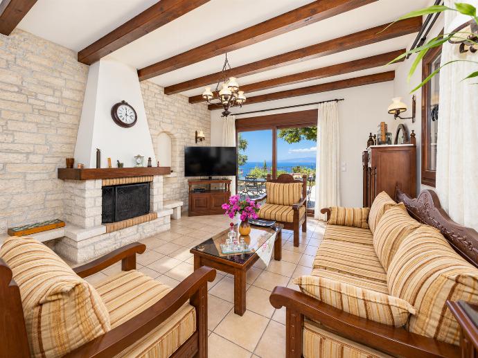 Open-plan living room with sofa, dining area, kitchen, ornamental fireplace, A/C, WiFi internet, satellite TV, and sea views . - Villa Ariadne . (Photo Gallery) }}
