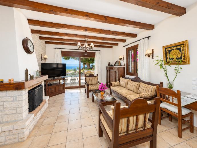 Open-plan living room with sofa, dining area, kitchen, ornamental fireplace, A/C, WiFi internet, satellite TV, and sea views . - Villa Ariadne . (Photo Gallery) }}