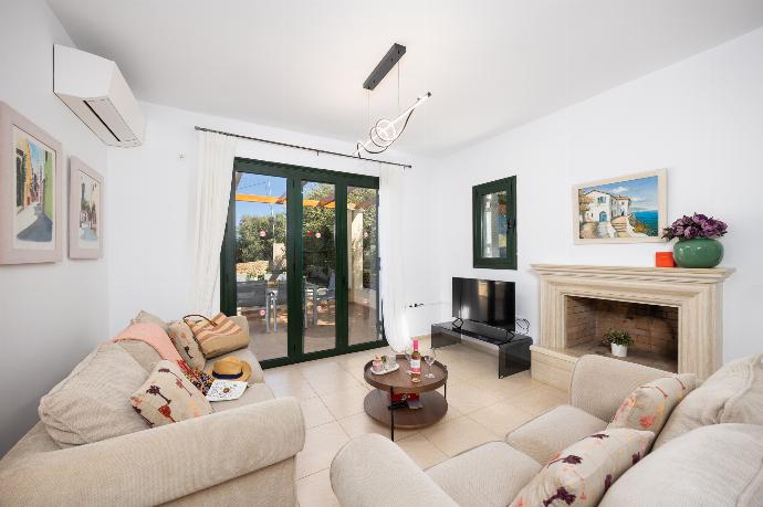 Open-plan living room with sofas, dining area, kitchen, ornamental fireplace, A/C, WiFi internet, satellite TV, and sea views . - Villa Eleni . (Photo Gallery) }}