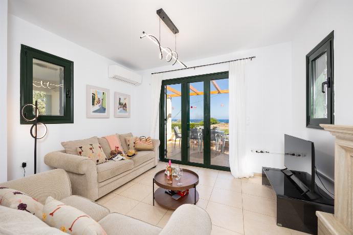 Open-plan living room with sofas, dining area, kitchen, ornamental fireplace, A/C, WiFi internet, satellite TV, and sea views . - Villa Eleni . (Photo Gallery) }}