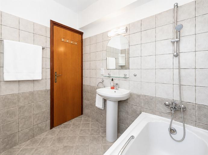 A classic tiled bathroom featuring a corner bathtub, pedestal sink with mirror, toilet, and vibrant yellow accent towels. . - Villa Argaka Heights . (Γκαλερί Φωτογραφιών) }}