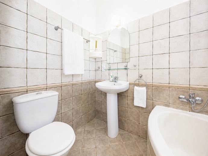 A bright, tiled villa bathroom featuring a built-in bathtub, a pedestal sink, a toilet, and vibrant pink accent towels. . - Villa Argaka Heights . (Γκαλερί Φωτογραφιών) }}