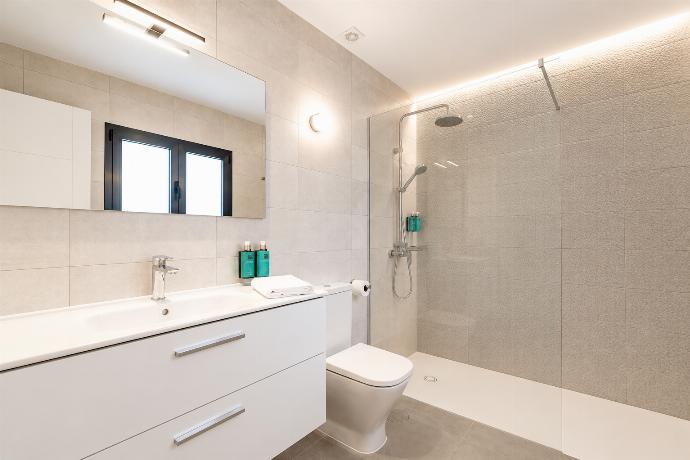 Modern bathroom with a spacious walk-in shower, sleek vanity, and warm ambient lighting. . - Ereza Residence 2.1 . (Photo Gallery) }}