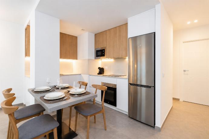 Modern open-plan kitchen and dining area with warm wooden cabinetry and a stylish table setting. . - Ereza Residence 3.1 . (Photo Gallery) }}