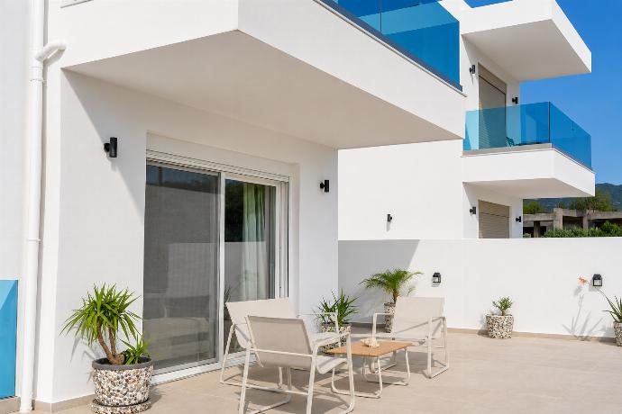 Sunny private terrace with modern seating, potted greenery, and sleek glass balconies. . - Villa Galini . (Galería de imágenes) }}