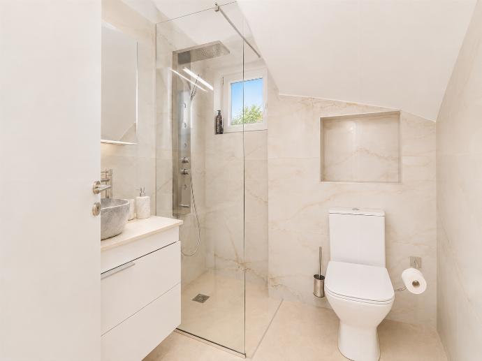 Modern bathroom with a walk-in glass shower, white vanity, and bright marble-style finishes. . - Villa Galini . (Galería de imágenes) }}