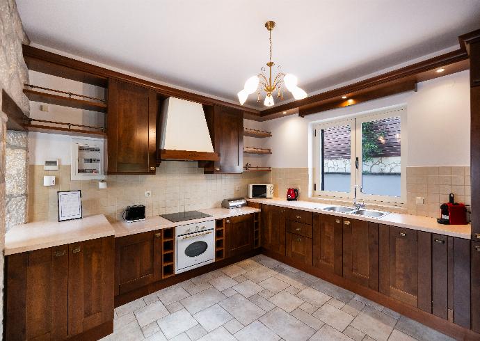 Fully equipped kitchen with rich wooden cabinetry and tiled flooring. . - Villa Galatia . (Photo Gallery) }}