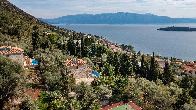 High-angle view of terraced hillside stone villas with private pools, a tennis court, and an ocean bay view. . - Villa Galatia . (Photo Gallery) }}