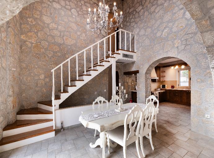 Stone dining room with a white table set beneath a staircase and crystal chandelier. . - Villa Galatia . (Photo Gallery) }}