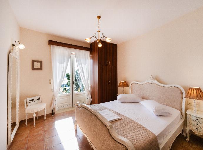 Bright bedroom featuring a classic upholstered bed frame and balcony doors. . - Villa Galatia . (Photo Gallery) }}