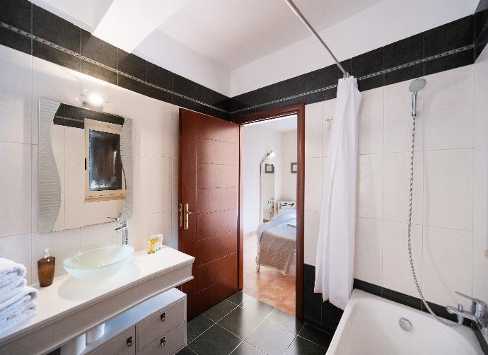 Modern bathroom with a black and white tiled design, bathtub, and glass vessel sink. . - Villa Galatia . (Photo Gallery) }}