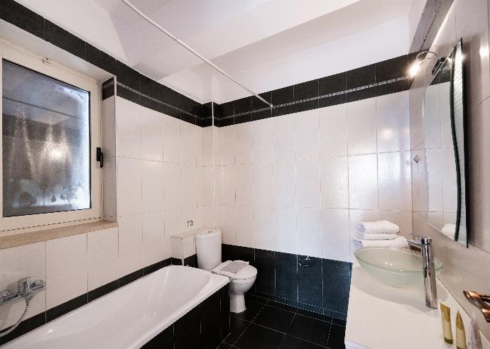 Modern bathroom featuring a black and white tiled design, toilet, and bathtub. . - Villa Galatia . (Photo Gallery) }}
