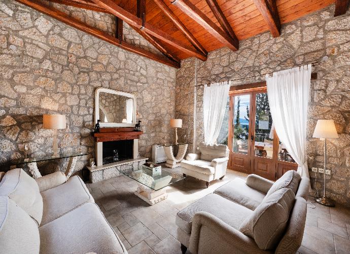 Stone living room with a vaulted wooden ceiling, fireplace, and cozy seating. . - Villa Galatia . (Photo Gallery) }}