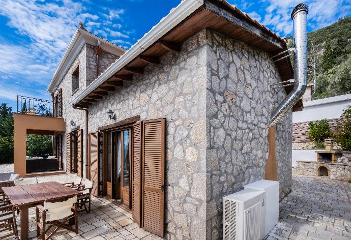 Stone villa terrace with a wooden dining set, window shutters, and a stone barbecue. . - Villa Galatia . (Photo Gallery) }}