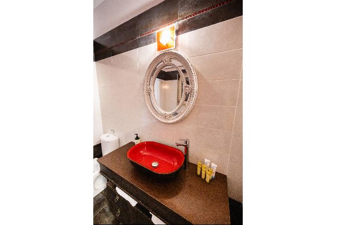 Modern vanity area featuring a vibrant red vessel sink and an ornate oval mirror. . - Villa Galatia . (Photo Gallery) }}