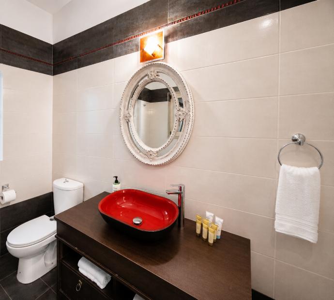 Modern vanity area featuring a vibrant red vessel sink and an ornate oval mirror. . - Villa Galatia . (Photo Gallery) }}