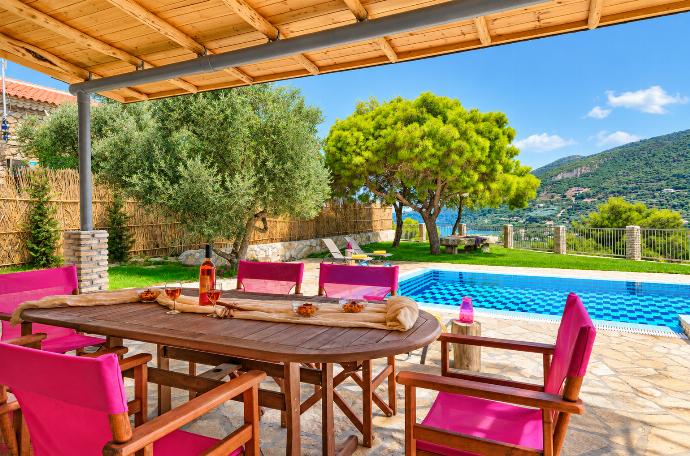 Covered outdoor dining terrace overlooking the private swimming pool, garden, and surrounding countryside.