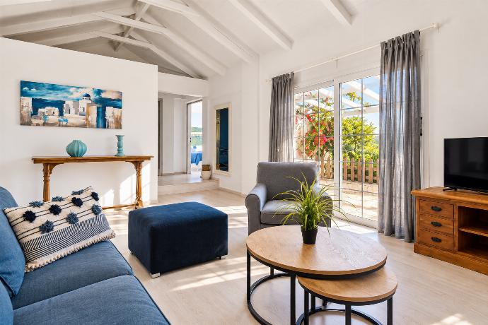 Stylish living room with comfortable seating, exposed ceiling beams, large windows, and direct access to the terrace.