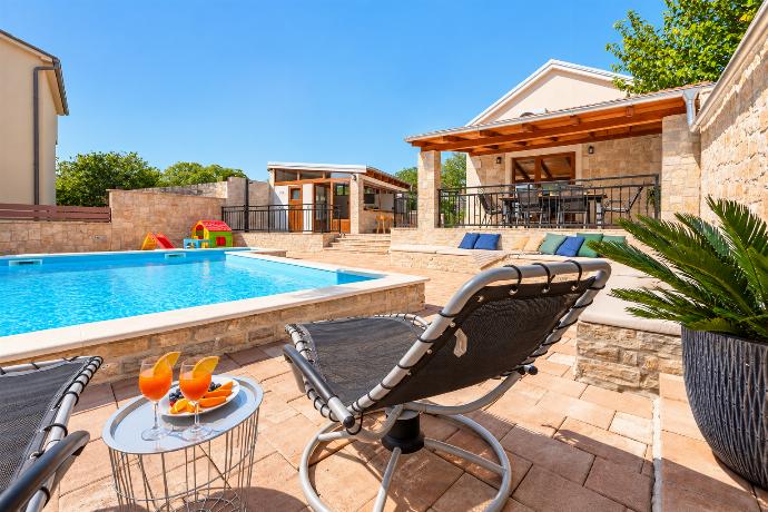 Private swimming pool with comfortable sun loungers, spacious terrace, and a charming stone villa backdrop.