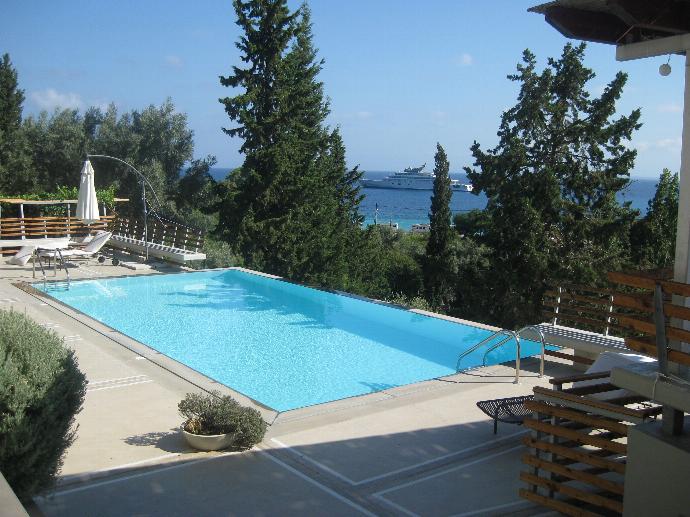 A sunlit outdoor swimming pool features lounge chairs and tall cypress trees overlooking a scenic sea view. . - Villa Santolina . (Galerie de photos) }}