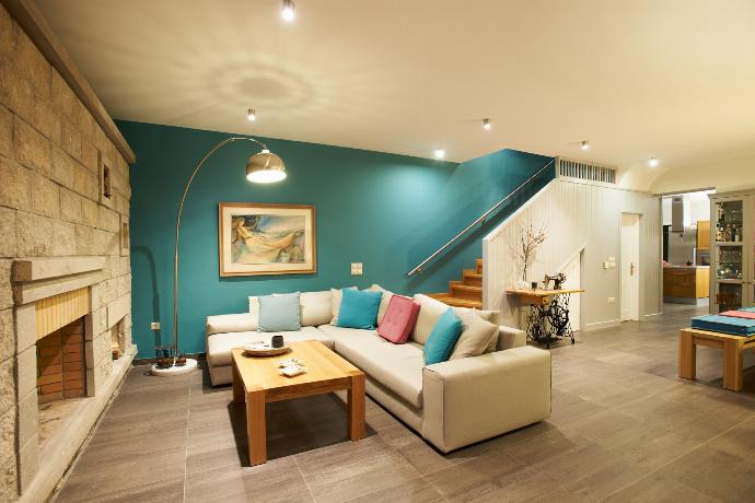 A spacious open-plan living room features a grey sectional sofa against a vibrant turquoise wall, an adjoining wooden dining set, and dark tiled flooring. . - Villa Santolina . (Galerie de photos) }}