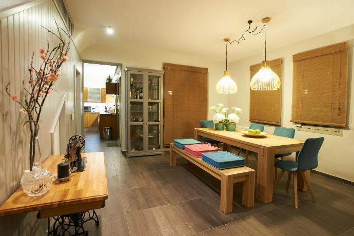 A wooden dining table is paired with a matching bench and turquoise chairs beneath warm pendant lights, located next to a grey display cabinet and sliding glass doors. . - Villa Santolina . (Galerie de photos) }}