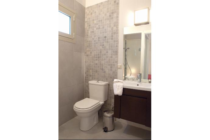 A modern bathroom features a compact dark vanity sink paired with a large mirror, neutral mosaic tiling, and clean white towels hanging nearby. . - Villa Santolina . (Galerie de photos) }}