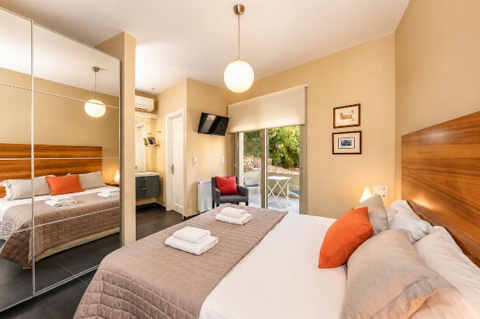 A bright bedroom features a double bed with a wooden headboard, a large mirrored wardrobe, and glass doors opening to a private outdoor seating area. . - Villa Oleana . (Galería de imágenes) }}