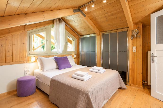 A rustic attic bedroom features wood-paneled walls and ceilings, a double bed with purple accent pillows, and tracking lights illuminating the sloped space. . - Villa Oleana . (Galería de imágenes) }}