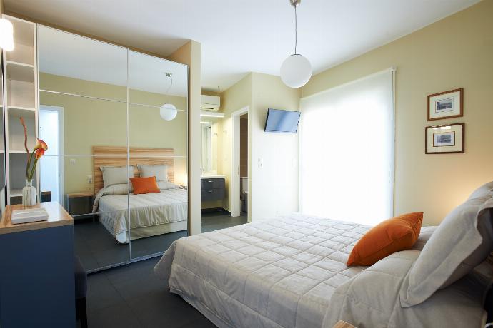 A bright bedroom features a double bed with a wooden headboard, a large mirrored wardrobe, and glass doors opening to a private outdoor seating area. . - Villa Oleana . (Galerie de photos) }}