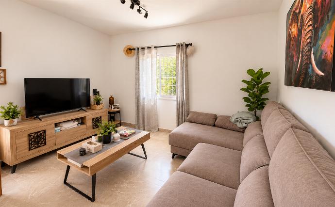 Modern living room with a spacious corner sofa, TV, coffee table, natural light, and stylish contemporary decor.