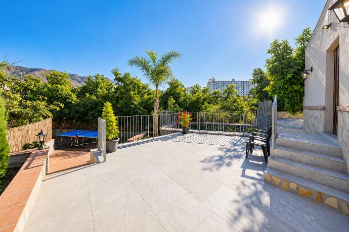 Spacious outdoor terrace with seating, landscaped greenery, palm trees, and views towards the private pool area.