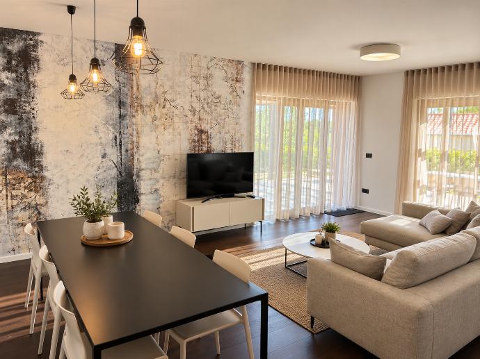 Bright open-plan living and dining area with comfortable seating, modern furnishings, wooden flooring, and contemporary decor.
