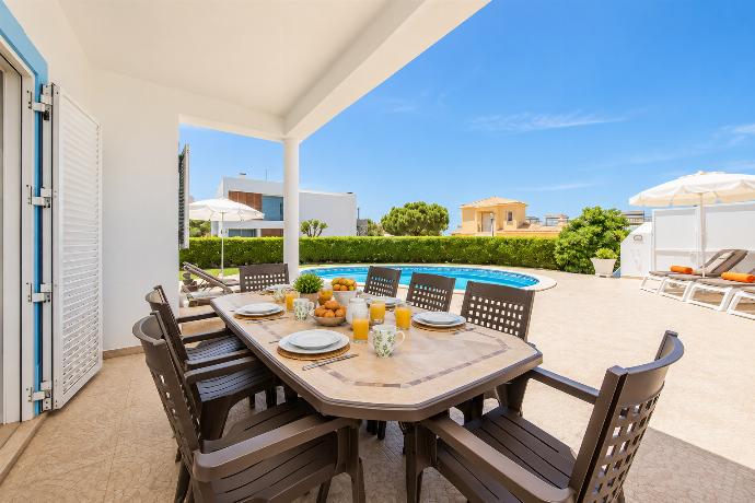 Outdoor dining area overlooking the private swimming pool, with comfortable seating and a spacious sun terrace.