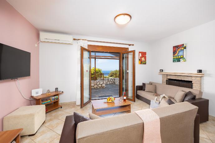 Open-plan living room with sofas, dining area, kitchen, ornamental fireplace, A/C, WiFi internet, and satellite TV . - Villa Yeraki . (Photo Gallery) }}