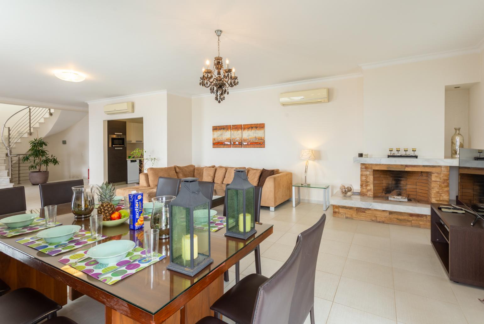 Open-plan living room with sofas, dining area, kitchen, ornamental fireplace, A/C, WiFi internet, satellite TV, and terrace access with sea views