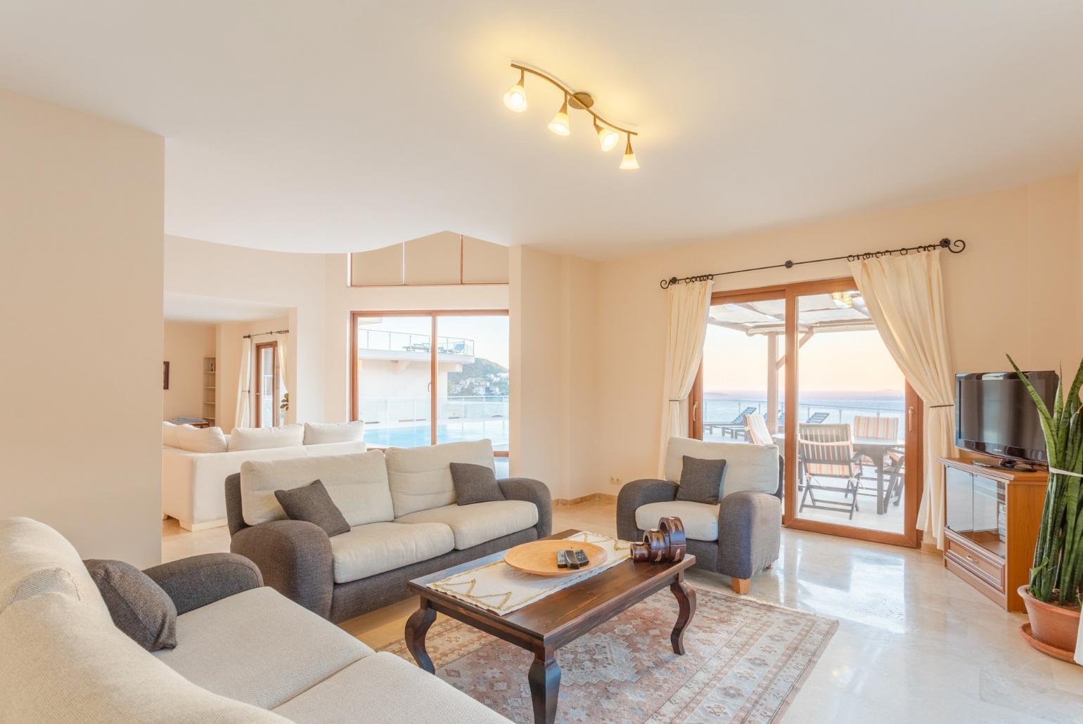 Open-plan living room with sofas, dining area, kitchen, A/C, WiFi internet, satellite TV, DVD player, and terrace access with panoramic sea views