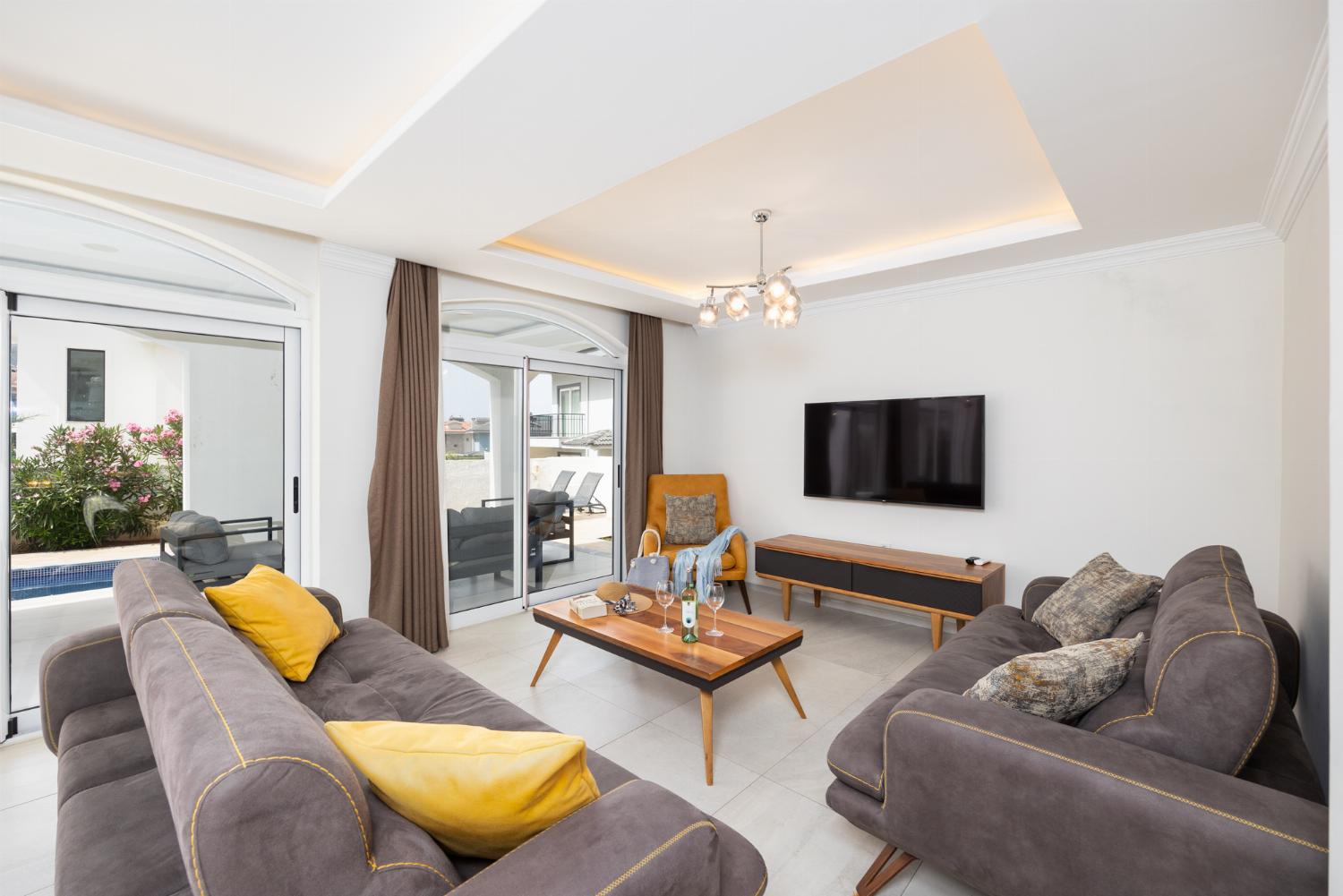 Open-plan living room with sofas, dining area, kitchen, A/C, WiFi internet, and satellite TV
