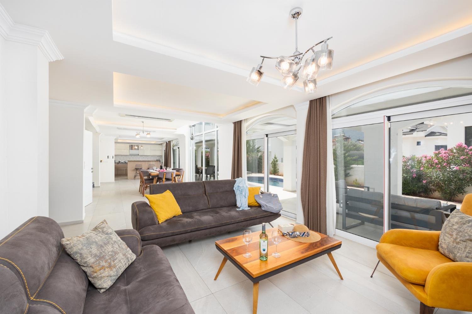 Open-plan living room with sofas, dining area, kitchen, A/C, WiFi internet, and satellite TV
