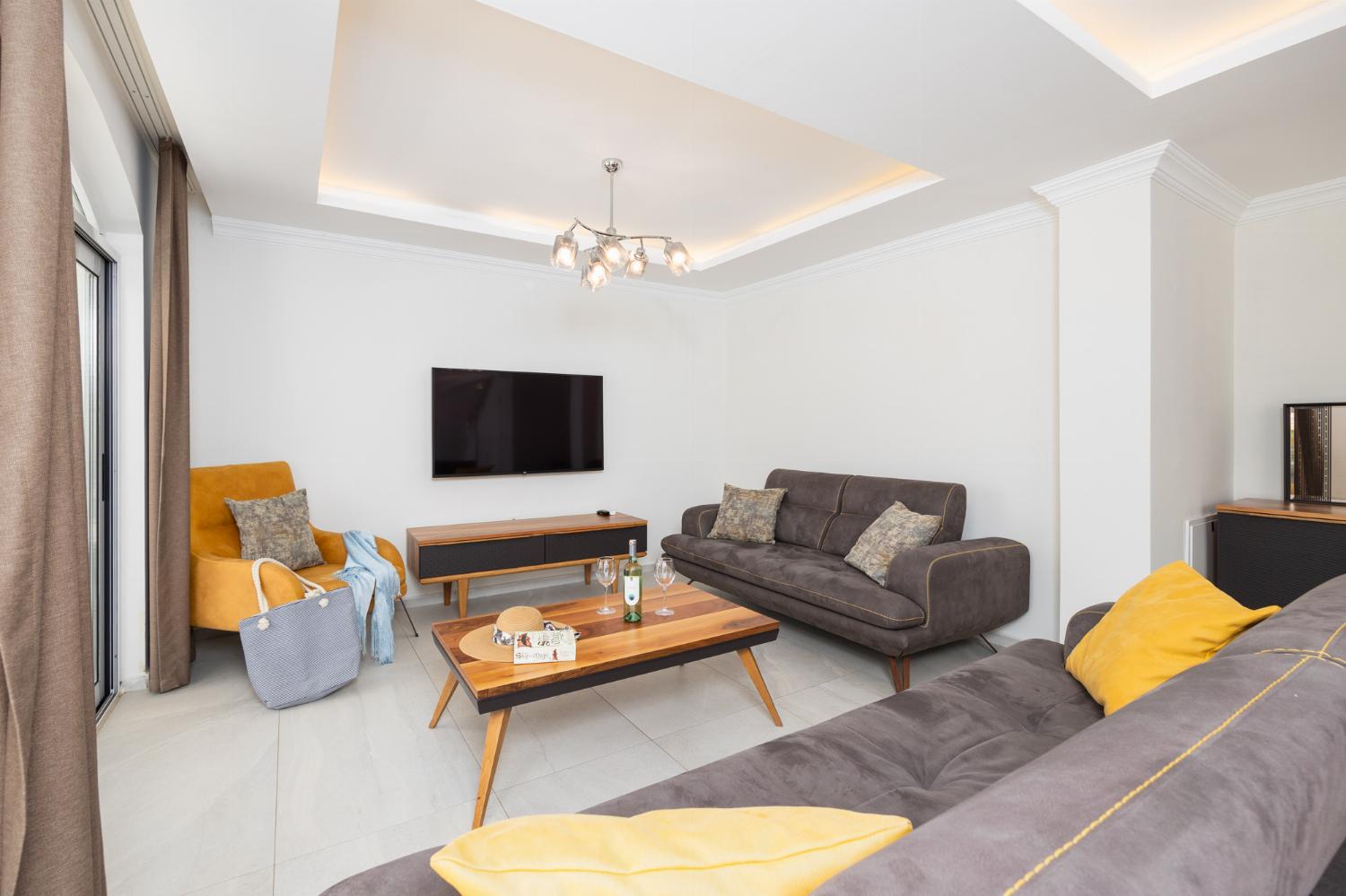 Open-plan living room with sofas, dining area, kitchen, A/C, WiFi internet, and satellite TV