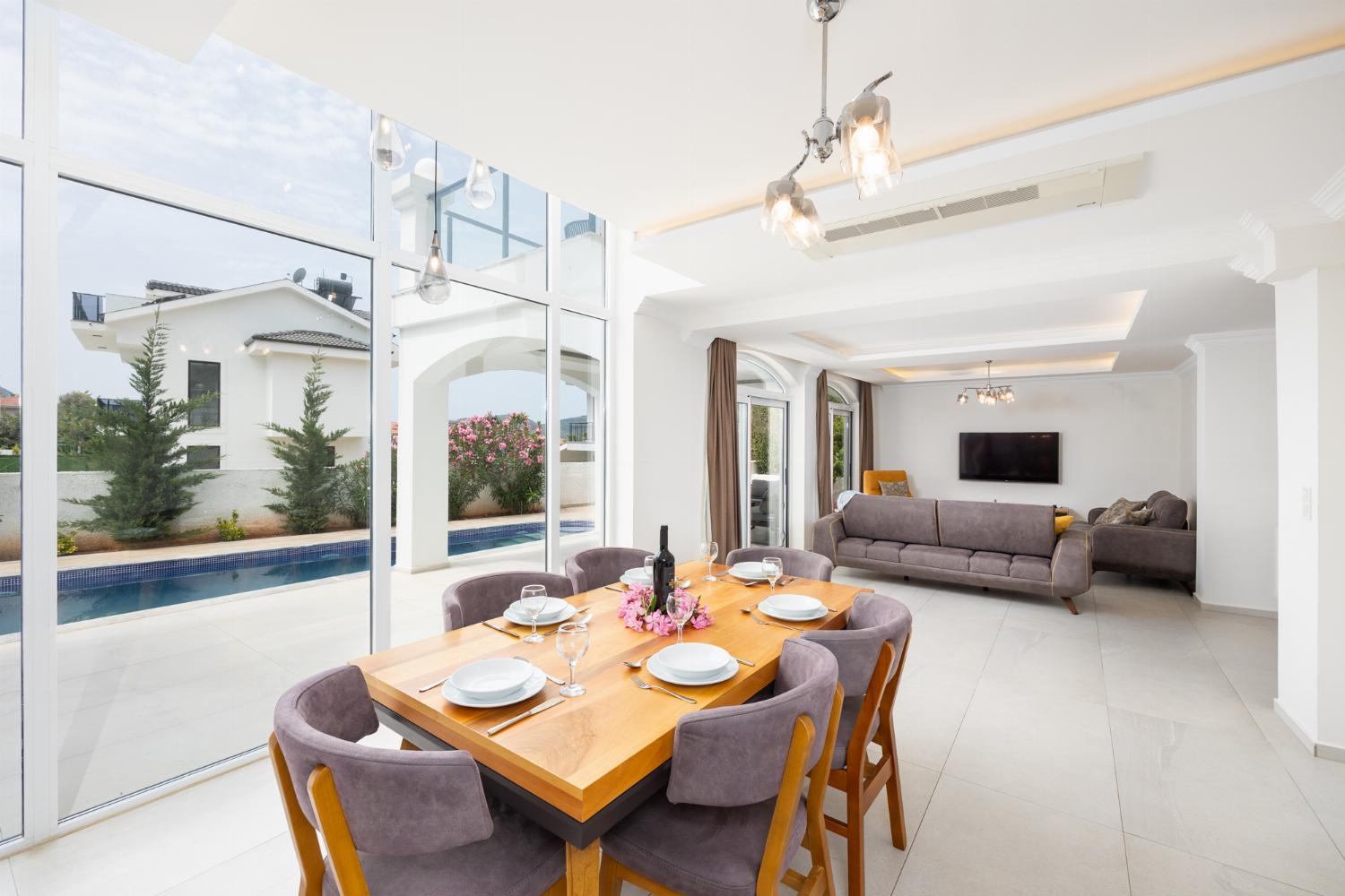 Open-plan living room with sofas, dining area, kitchen, A/C, WiFi internet, and satellite TV