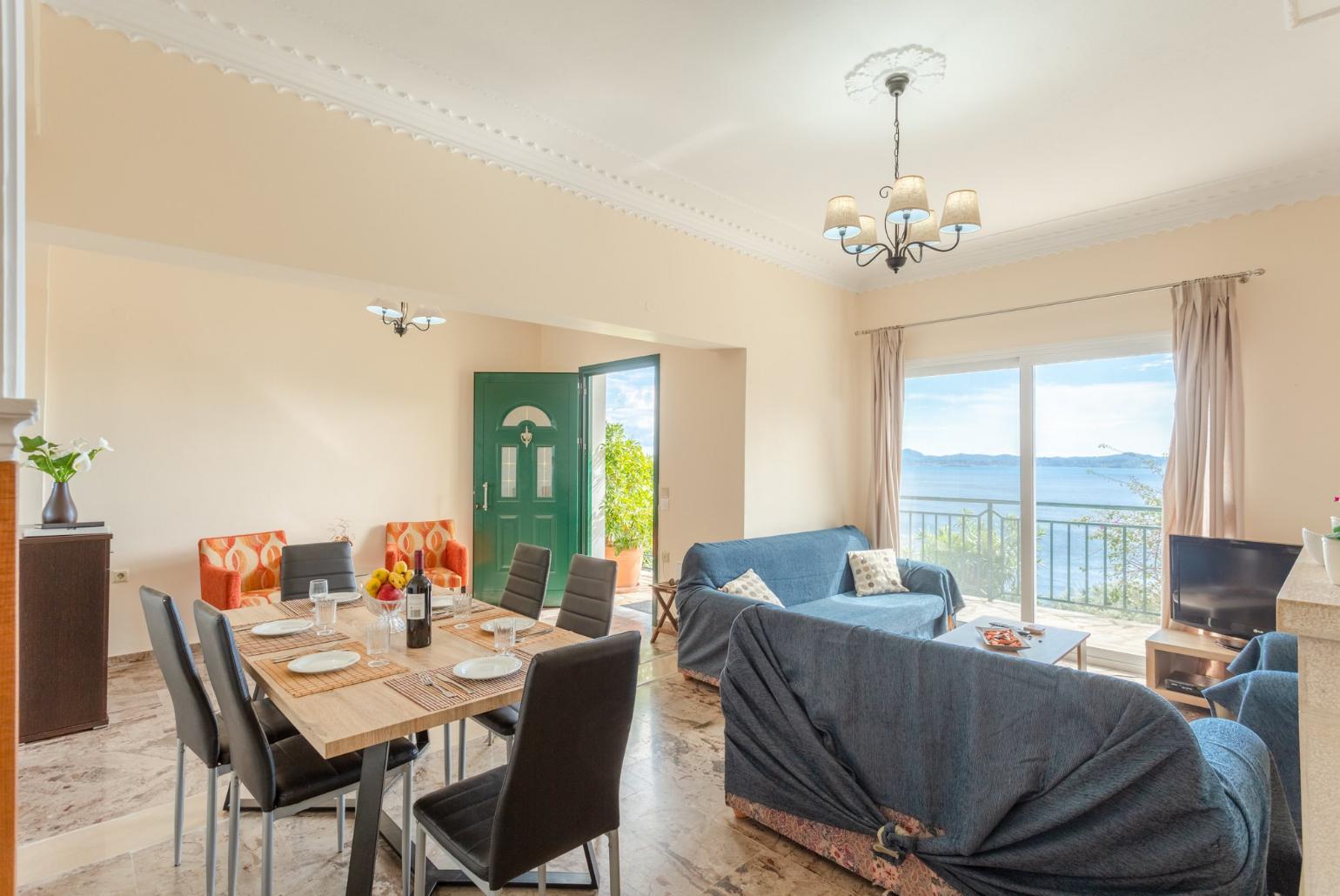 Open-plan living room with sofas, dining area, kitchen, ornamental fireplace, WiFi internet, satellite TV, DVD player, and terrace access with sea views