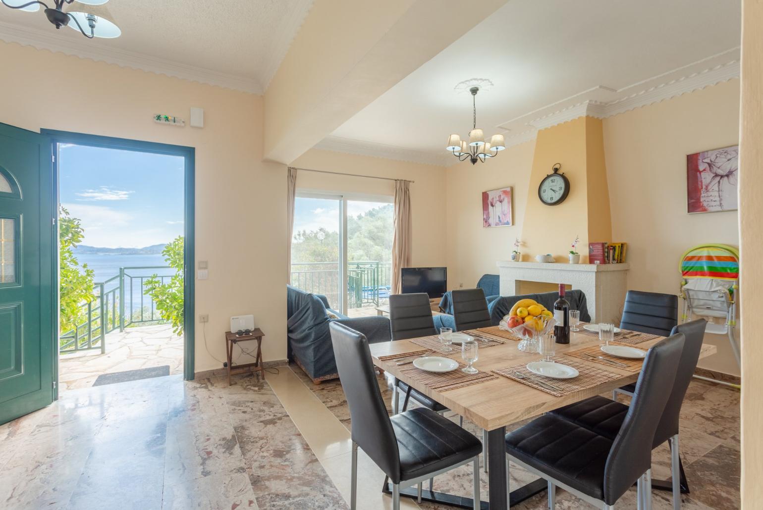 Open-plan living room with sofas, dining area, kitchen, ornamental fireplace, WiFi internet, satellite TV, DVD player, and terrace access with sea views