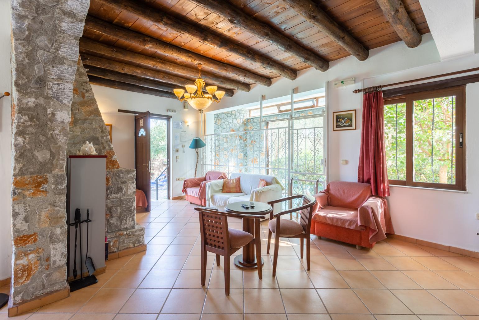 Open-plan living room with sofas, dining area, kitchen, ornamental fireplace, indoor pool, WiFi internet, satellite TV, DVD player, and terrace access